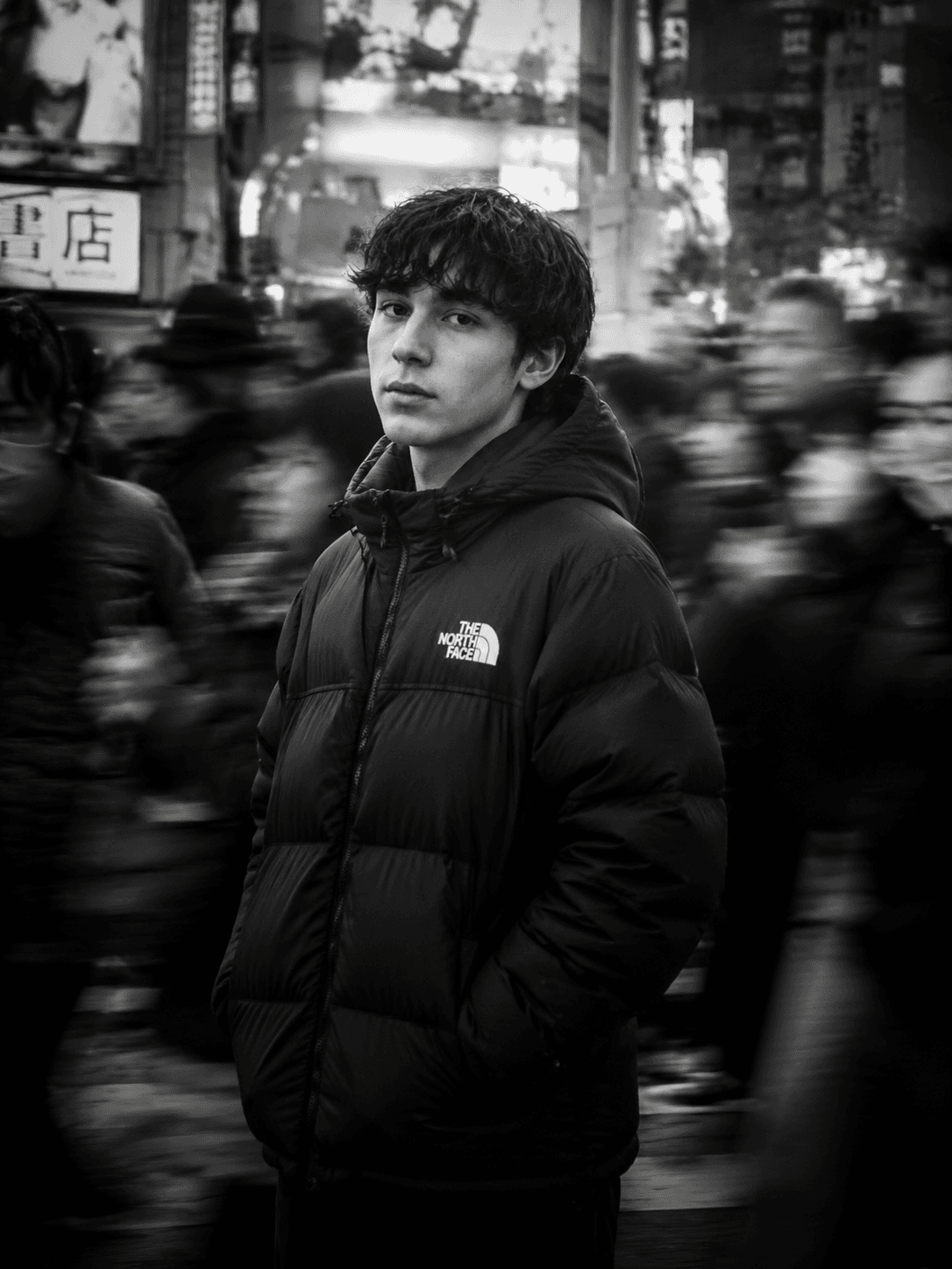 Black-and-white cinematic portrait of a young person in a The North Face puffer